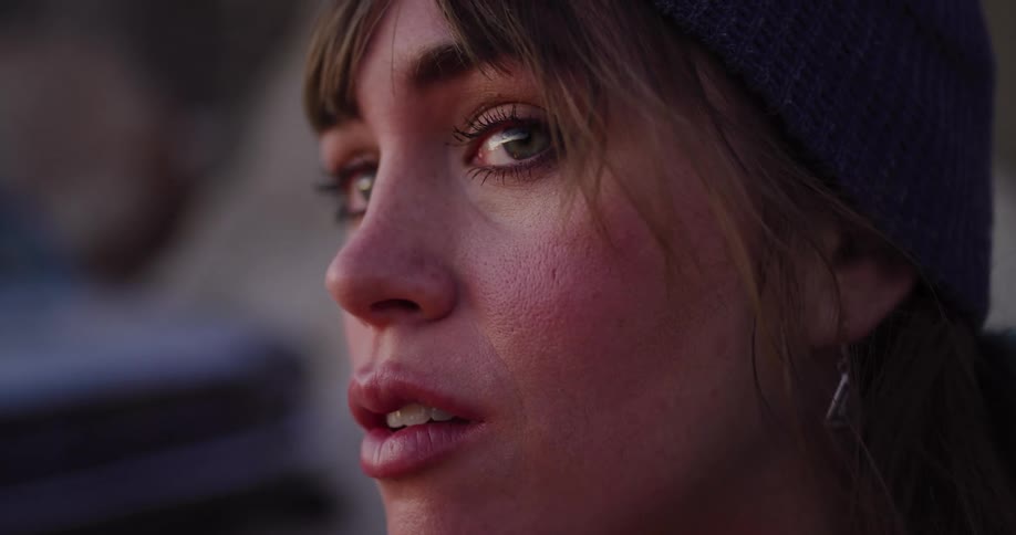 Close-up slow motion of a woman wearing a beanie opening her eyes and looking out with wonder at sunset