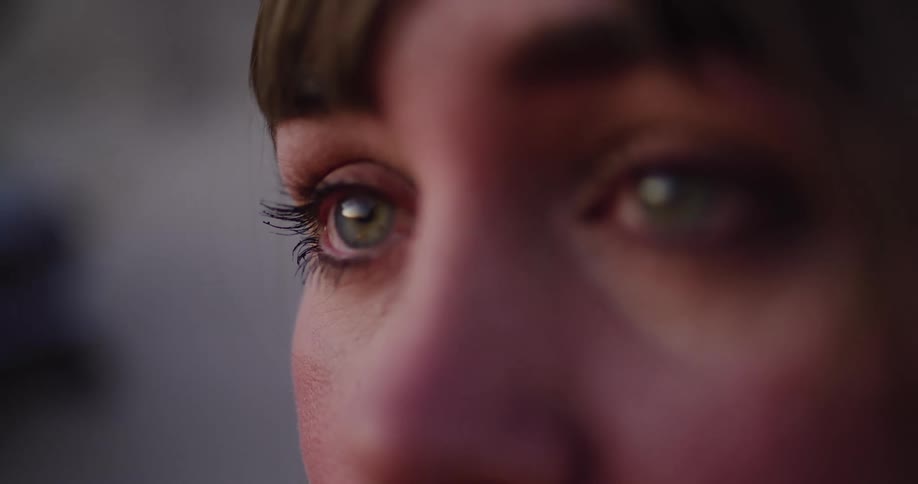 An extreme close-up of a woman's beautiful green eyes, looking off with a pensive and emotional expression