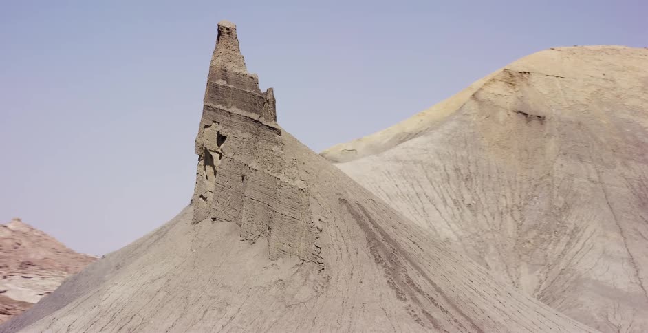 A slow reveal of a unique geological rock formation in the vast, arid desert badlands of the American West