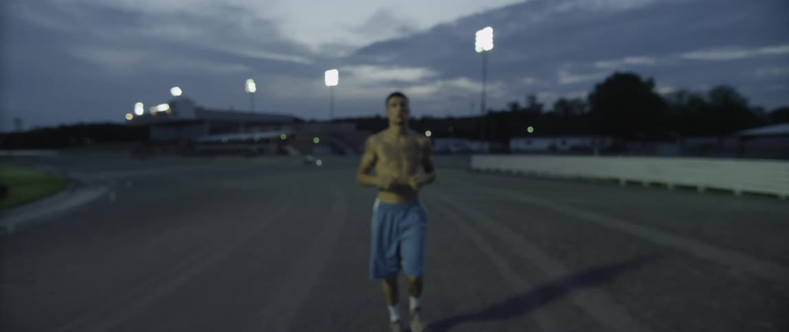 Man running towards the camera on a track under sports lights