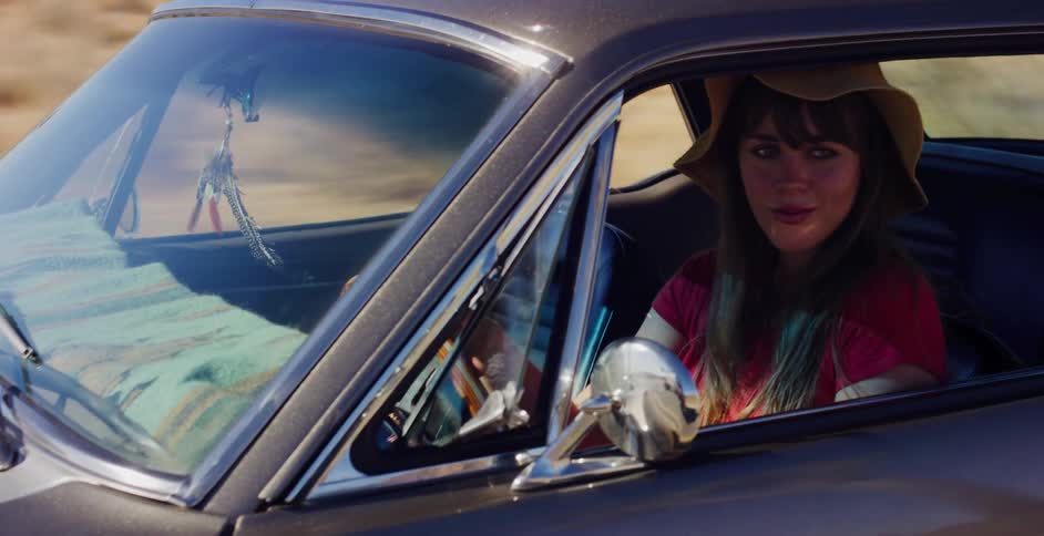 A stylish woman in a hat enjoys driving her classic black car on a sunny day