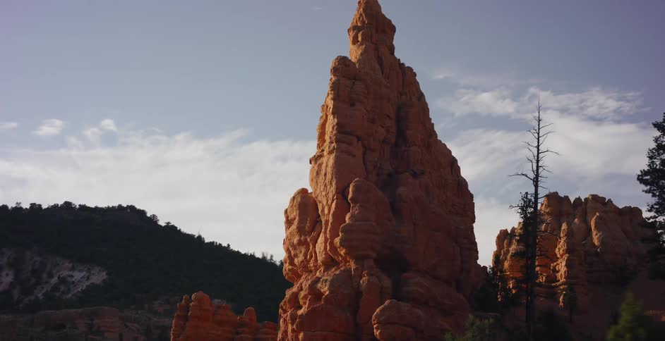 A slow push-in shot captures the magnificent detail of a towering red rock hoodoo in a desert canyon at golden hour
