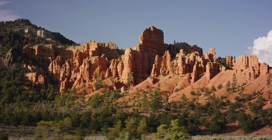 Driving past the stunning red rock hoodoos of a desert canyon on a sunny day
