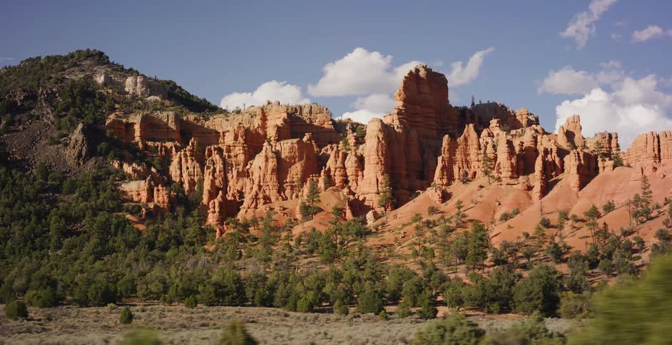 Driving past the majestic red rock spires and hoodoos of a desert canyon in Utah on a beautiful sunny day