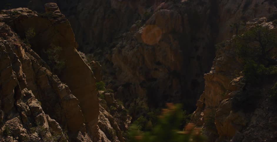 A sweeping cinematic pan up reveals the majestic beauty of a rugged mountain canyon at golden hour