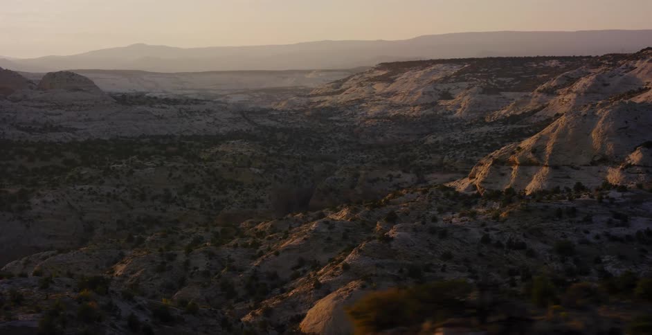 A majestic view of a vast, rocky desert canyon landscape bathed in the warm light of sunrise