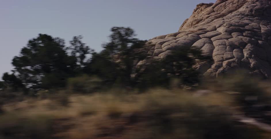 Driving past a unique and textured sandstone butte with polygonal cracking in the desert