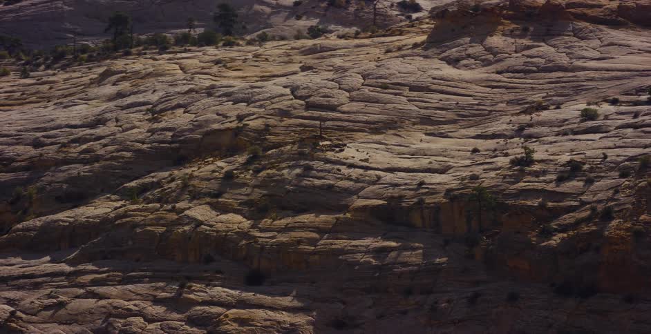 A detailed view of a vast, weathered rock formation in a sunlit desert canyon landscape