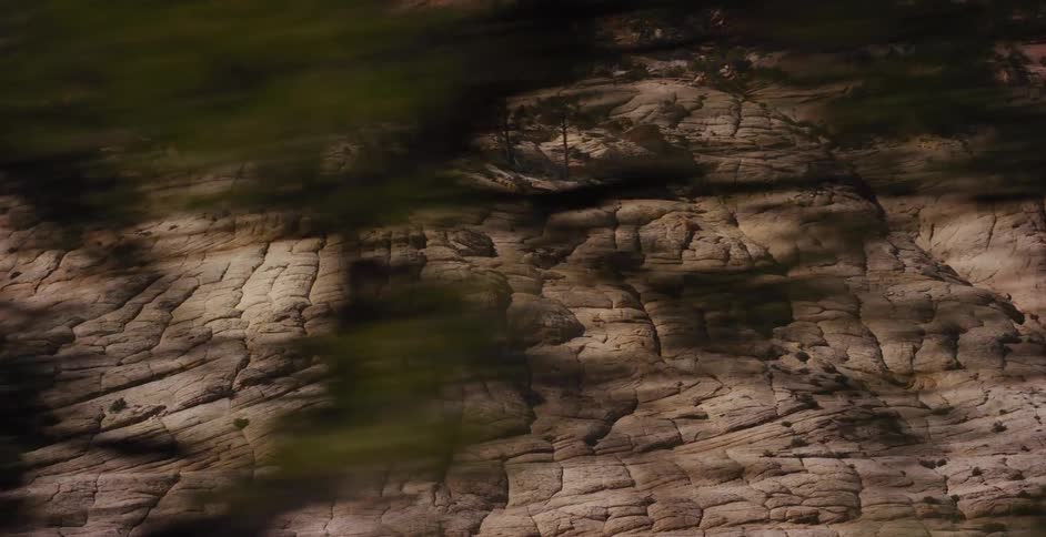A slow pan reveals the unique cross-hatched patterns of a sandstone mountain in a desert landscape
