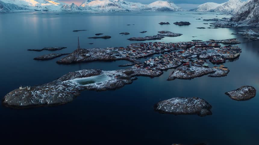 A time-lapse aerial view shows the snowy island village of Henningsvaer in the Lofoten Islands of Norway as day turns to night