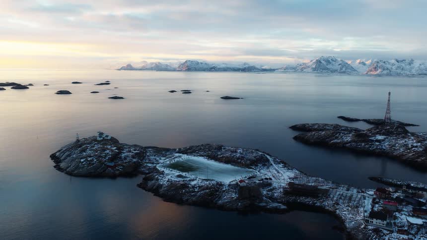 Breathtaking aerial view of a unique football pitch on a snowy island in Norway as the sun rises over the dramatic mountain landscape