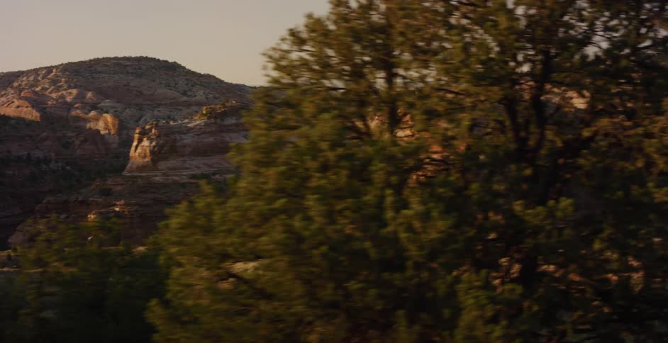 A scenic panning shot reveals a vast desert canyon landscape during a beautiful golden hour
