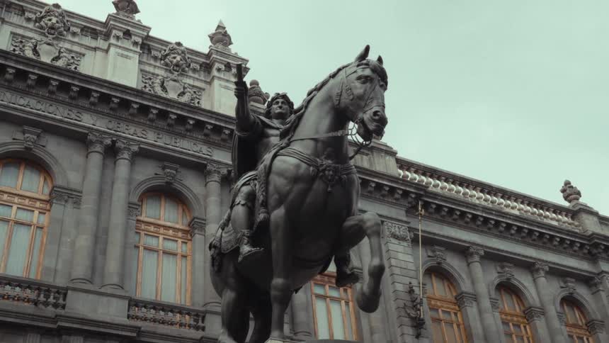 A slow zoom out from the bronze equestrian statue of El Caballito in front of the National Museum of Art in Mexico City