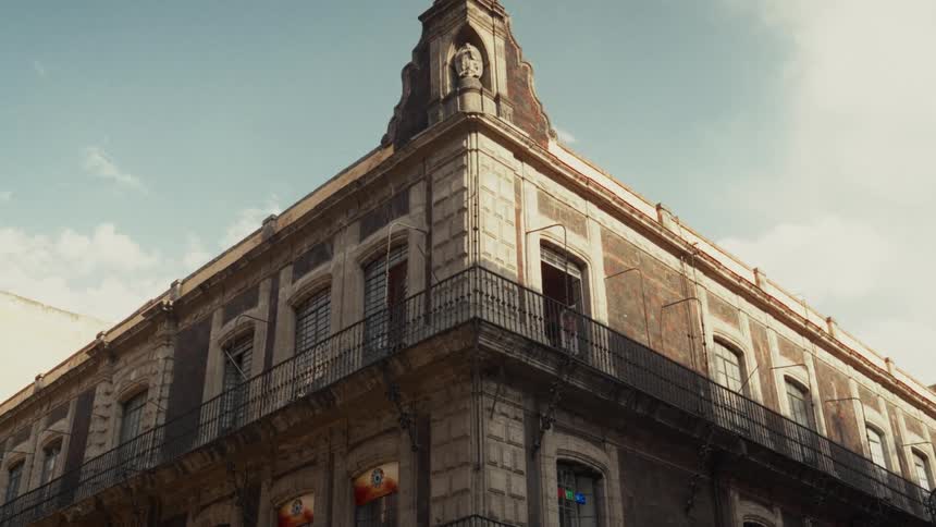Warm sunlight illuminates the ornate architecture of a historic corner building while a pedestrian passes by