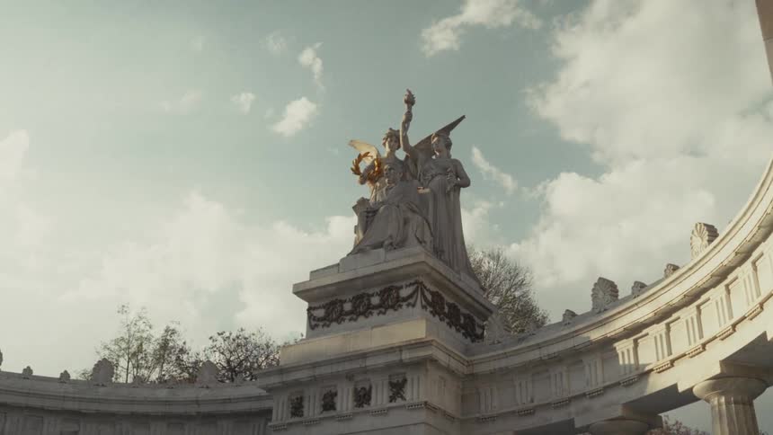 A cinematic slow pan revealing the majestic Hemiciclo a Juárez monument in Mexico City bathed in warm sunlight