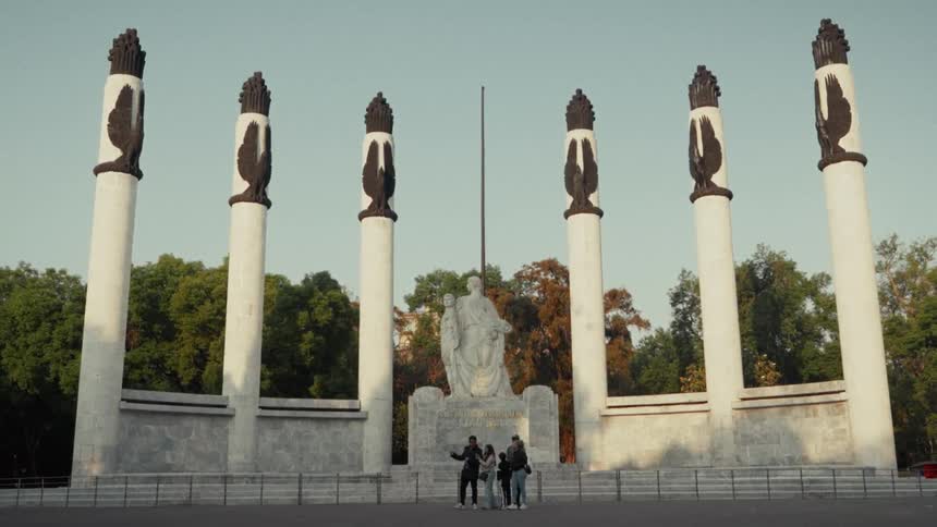 A group of young tourists take photos in front of the iconic Monumento a los Niños Héroes in Mexico City