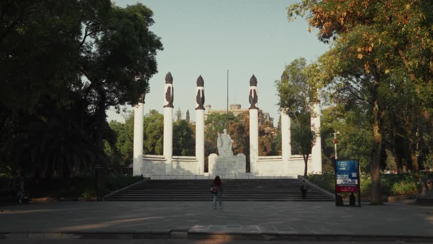 A young woman with red hair walks towards the Monumento a los Niños Héroes in Chapultepec Park, Mexico City