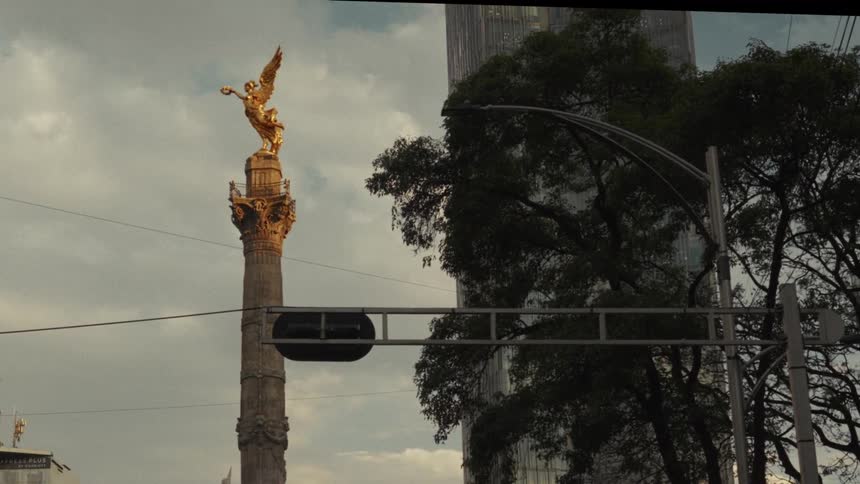 Static time-lapse shot of Mexico City's iconic Angel of Independence monument at dusk with a modern skyscraper in the background