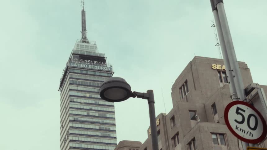 A slow dolly shot reveals the iconic Torre Latinoamericana and a classic Sears building against an overcast sky in Mexico City