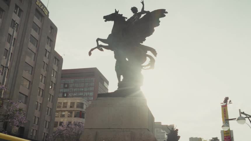 The majestic Pegasus statue in Mexico City is silhouetted as the sun flares from behind it in a cinematic shot