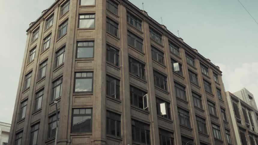 A slow upward tilt reveals the classic stone facade of an old city building against the sky
