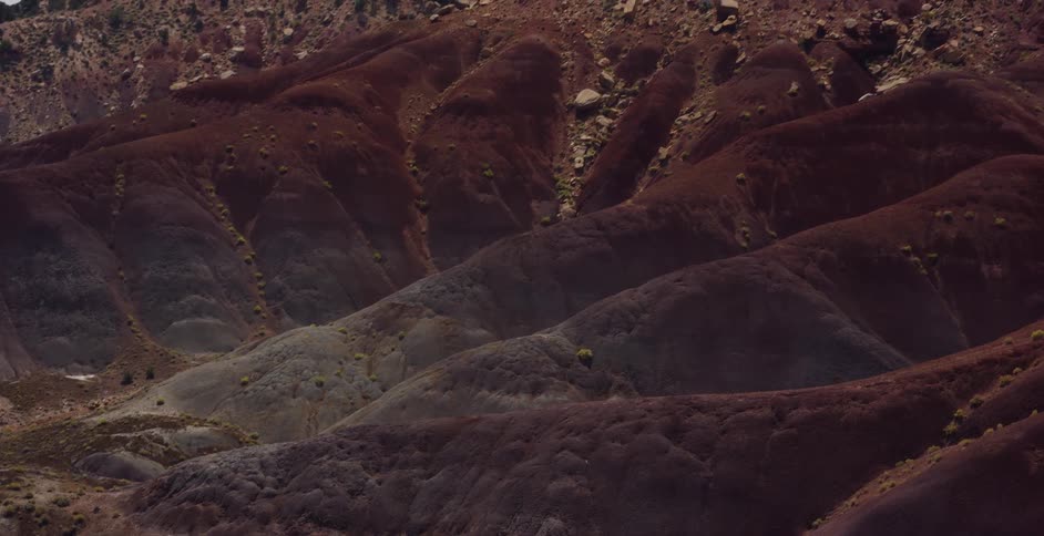 A slow tilt-up reveals the uniquely colored, eroded, and layered hills of a desert badlands landscape
