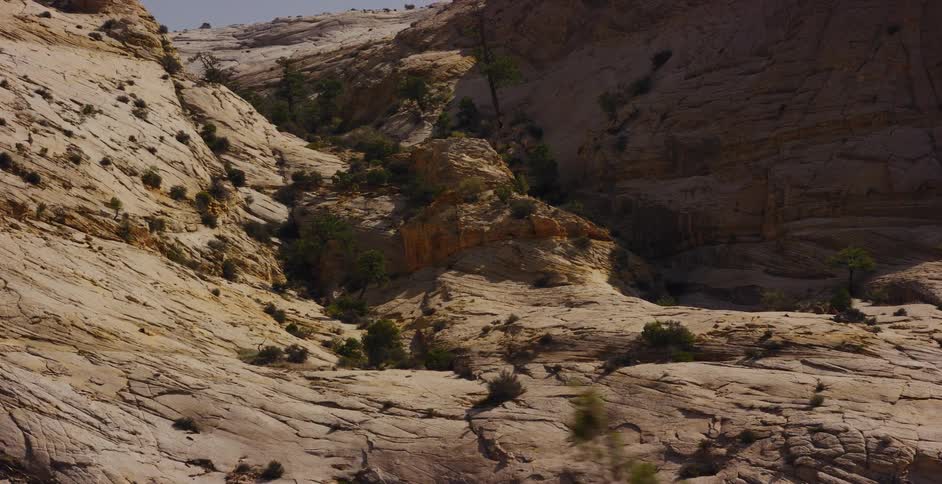 Sunlight and shadows move across the arid, rocky landscape of a sandstone canyon