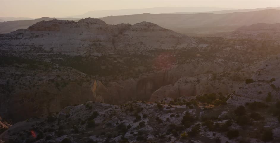 Driving past a majestic desert canyon landscape at sunrise, with warm golden light illuminating the vast and rugged terrain