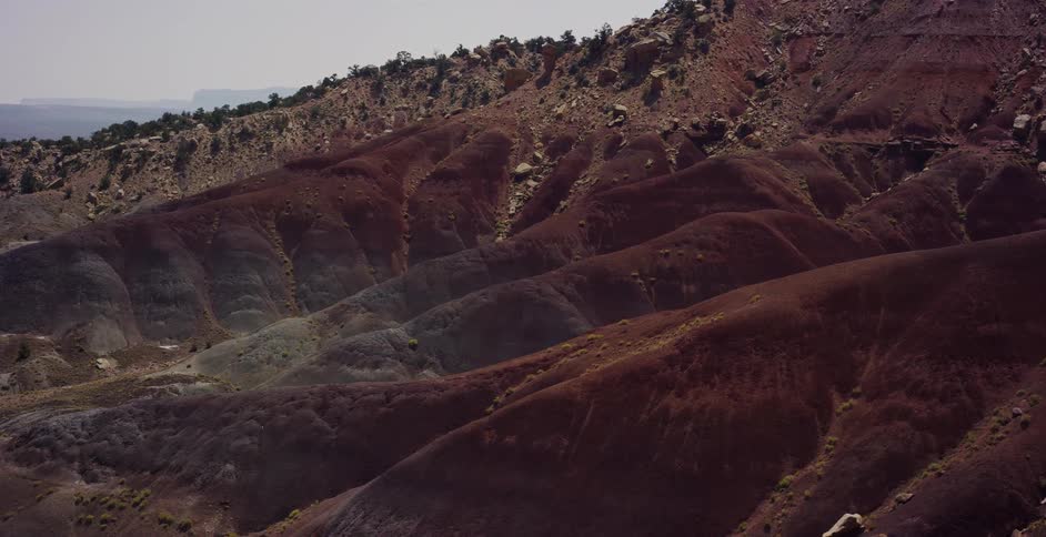 A wide shot slowly zooms in on the stunning, multicolored layers of rolling hills in a desert badlands landscape