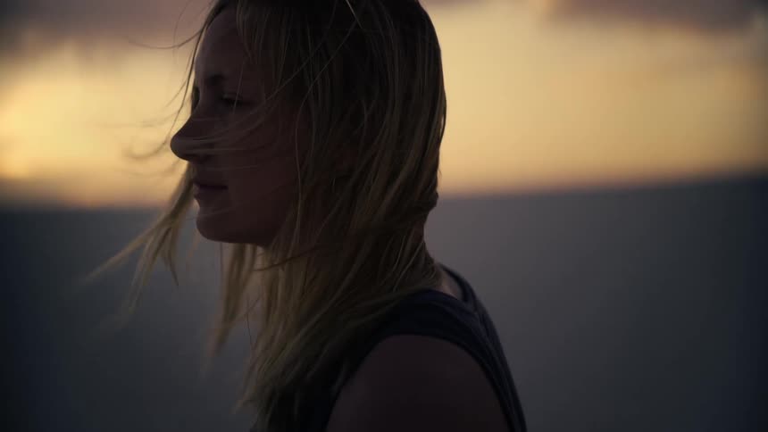 Cinemagraph loop of a woman's hair gently blowing in the wind during a peaceful sunset