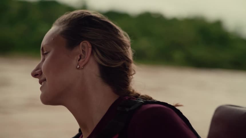 Carefree woman smiles with her eyes closed, feeling the wind in her braided hair during a slow-motion boat journey