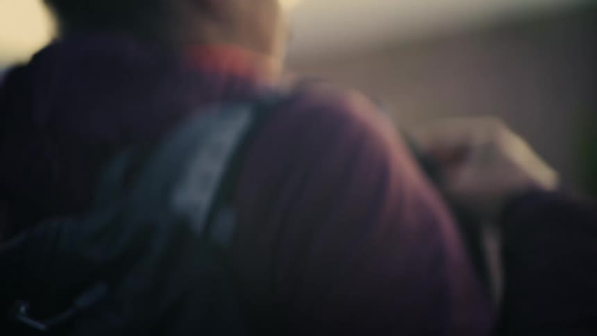 Slow motion close up shot of a female hiker putting on her backpack and preparing for a trek in the wilderness