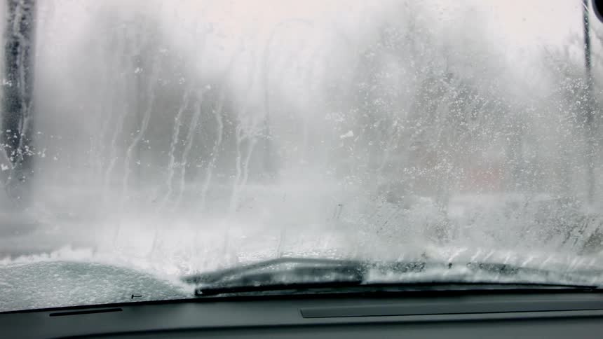 Windshield wipers clear snow from a windshield