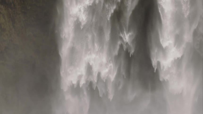 Mesmerizing slow-motion footage shows a powerful waterfall creating an immense cloud of mist as it flows down a rocky cliff
