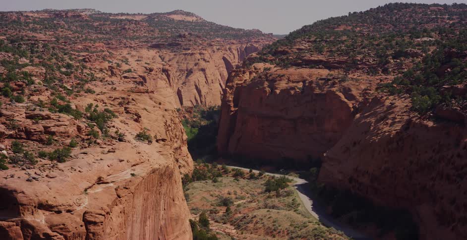 A smooth tracking shot from a vehicle reveals the expansive and majestic beauty of a red rock canyon on a sunny day