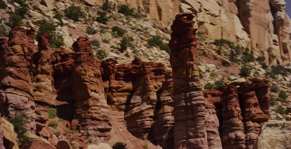Cinematic tracking shot of towering red rock hoodoos and geological formations in a Southwestern canyon