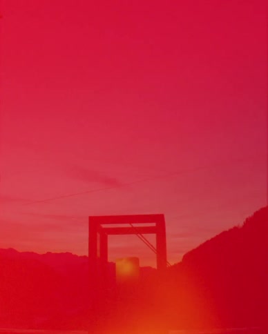A vintage-style vertical shot transitions through color flares to a serene mountain sunset with a candlelit lantern in the foreground