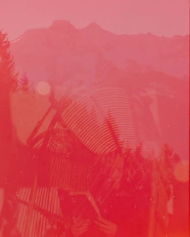 A vintage photograph of a person reading a book with a snowy mountain background is exposed by a warm film burn effect