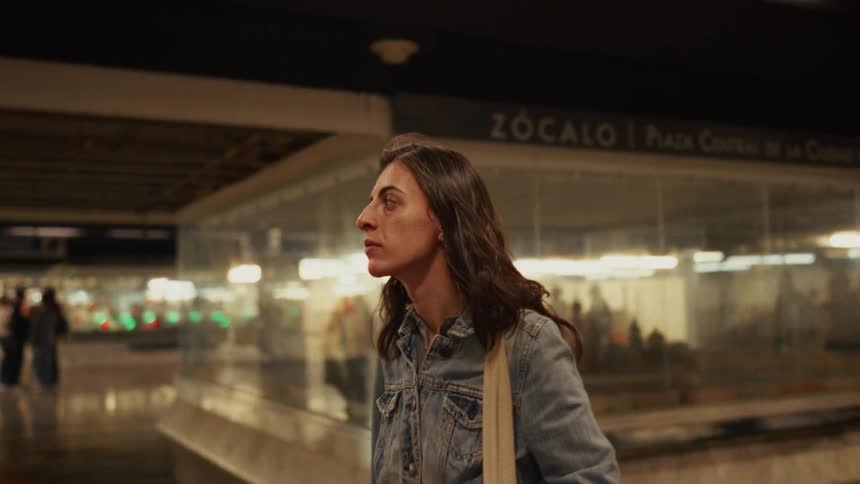 Slow motion shot of a woman looking around while waiting in the Zócalo metro station in Mexico City