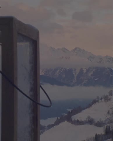 A snowy lantern sits in front of a stunning, snow-covered mountain landscape at dusk