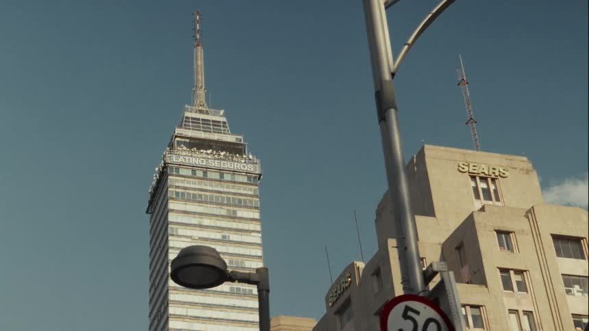 A slow, low-angle slider shot reveals the iconic Torre Latinoamericana against a clear blue sky in Mexico City