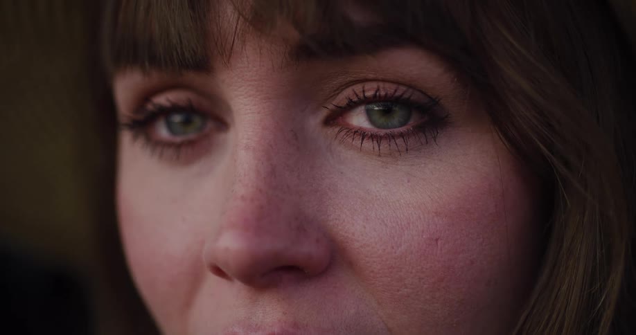 An emotional close-up slow-motion shot of a sad woman's green eyes welling up with tears
