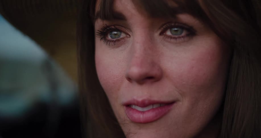 An extreme close-up shot captures the subtle, emotional expression of a woman with green eyes