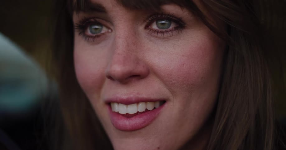 Extreme close-up on the emotional face of a woman with green eyes as she looks at something with wonder and tears welling up