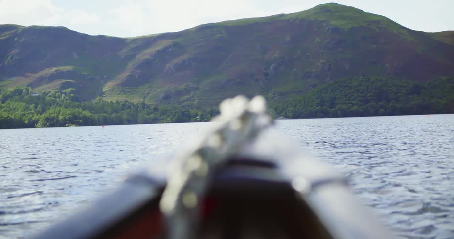 A boat is floating in the waters off a hilly coast