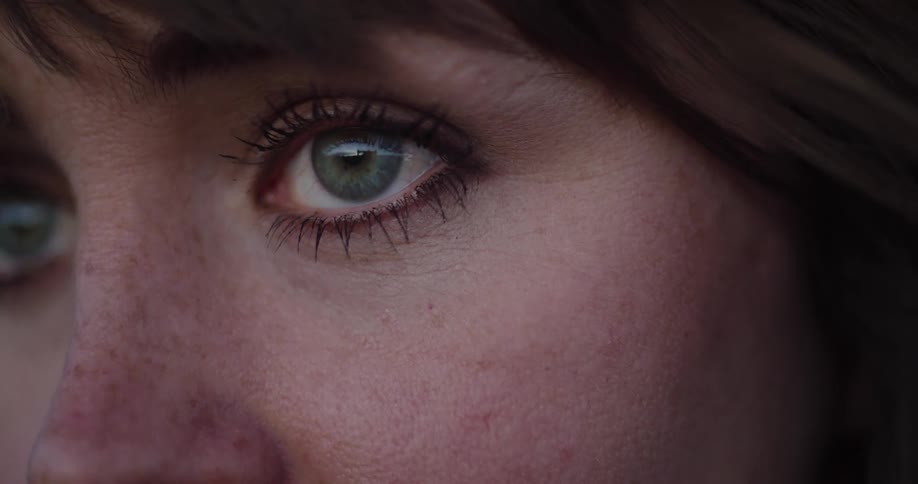A detailed close-up of a woman's beautiful green eyes as she gazes pensively