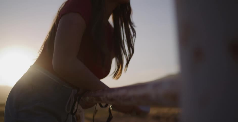 A smiling woman in a hat takes pictures with her instant camera while enjoying the golden hour light outdoors