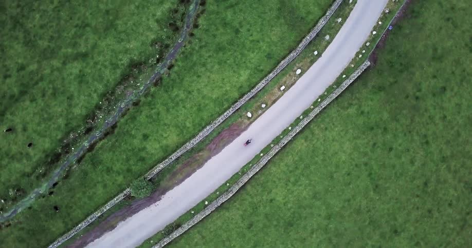 A bicyclist travels down the middle of a rural road