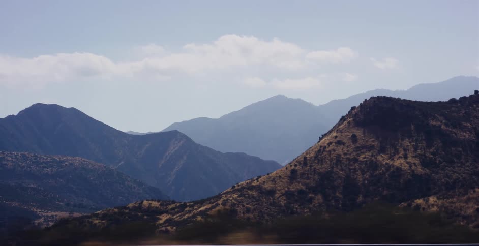 Layers of hazy blue and brown mountains stretch across the landscape under a soft sky
