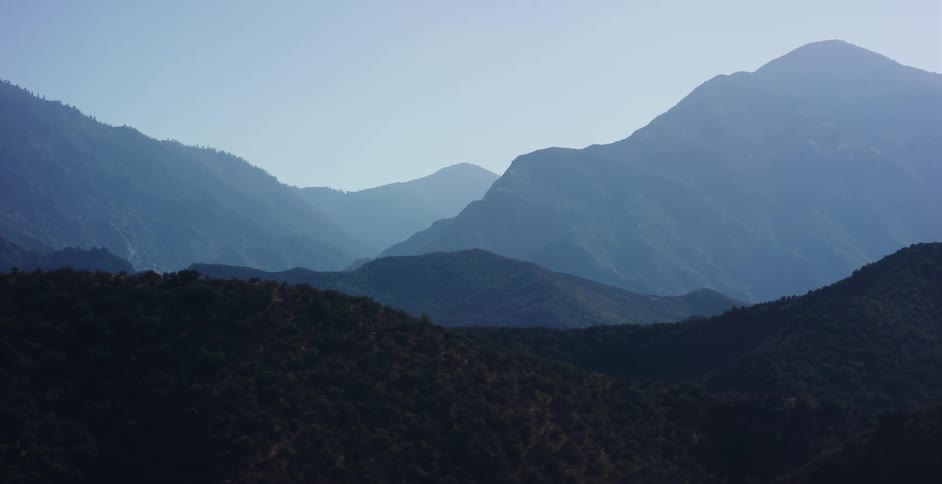 Hazy blue mountain ranges create majestic layers under a clear morning sky